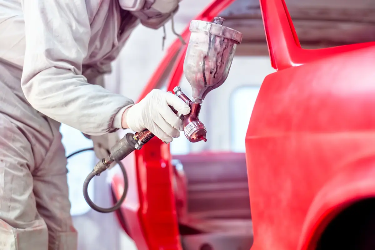 professional-worker-spraying-red-paint-on-a-car